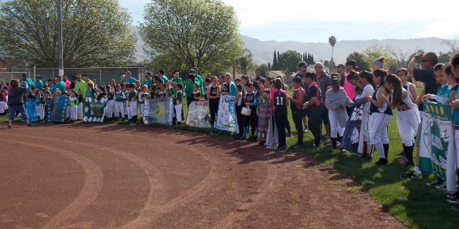 Teams lined up around the infield for their league's opening day ceremony.