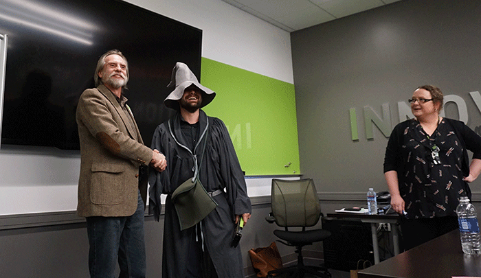 Entisys 虚拟实践项目经理 Dane Young 穿着灰袍、戴着破旧的锥形帽，向资深社区成员 Tobias Kriedl 介绍 Tesla GPU。