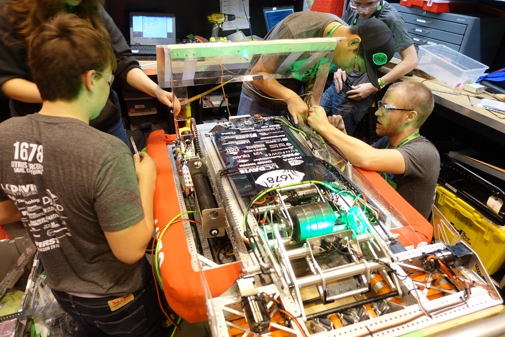 来自加利福尼亚戴维斯市戴维斯高级中学的 Citrus Circuits 团队在圣路易斯的 FIRST 机器人大赛中制造他们的机器人。