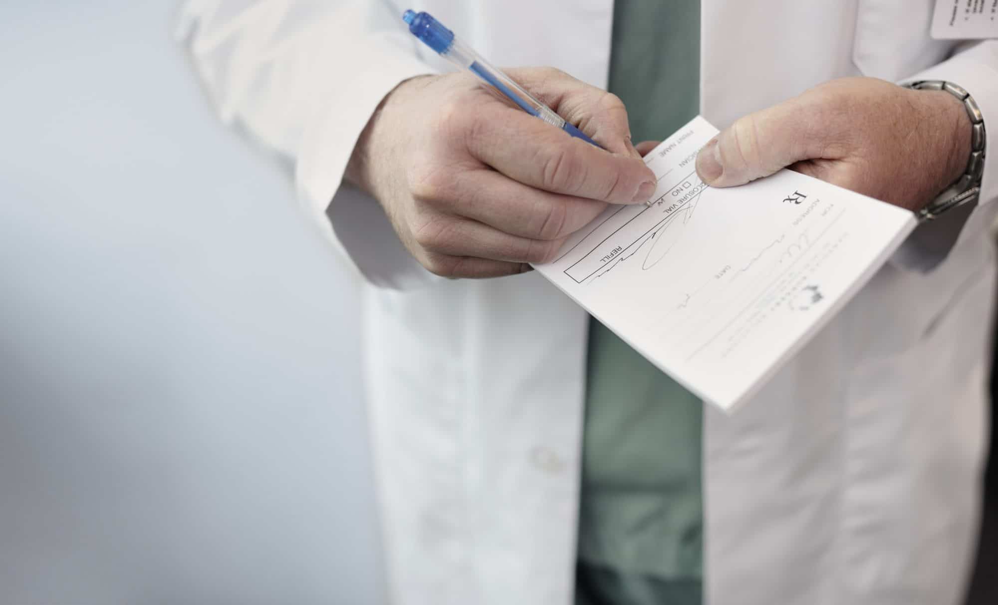 Close up of a male doctor filling out a medical prescription