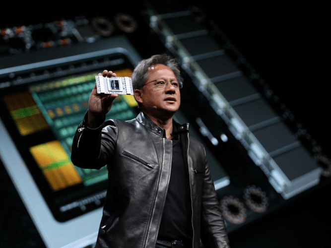 「Volta」のチップを手に持ち発表する NVIDIA の創設者兼 CEO、ジェンスン フアンの写真